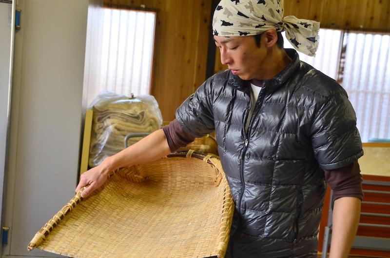 穀箕（こくみ）を持つ９代目の川口恭さん。夏は農家として、無農薬の野菜づくりに精を出す