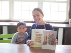 新居にて著書を手に次男君と。長男君はもう幼稚園ですが、2歳の次男君は吉永さんがお仕事の時も一緒。「手づくりの幸せを広めたい！」と精力的に活動されながらも「家族が一番大切！」と明言する吉永さんです。