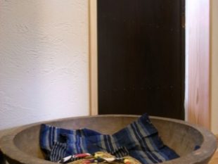 洗面所の建具はアンティーク。片山さんが選んできたものに合わせて戸の框を設計できるのも、オーダーメイドのリフォームならでは。やはり骨董のこね鉢をスリッパ置きにして、玄関回り全体の統一感が出た
